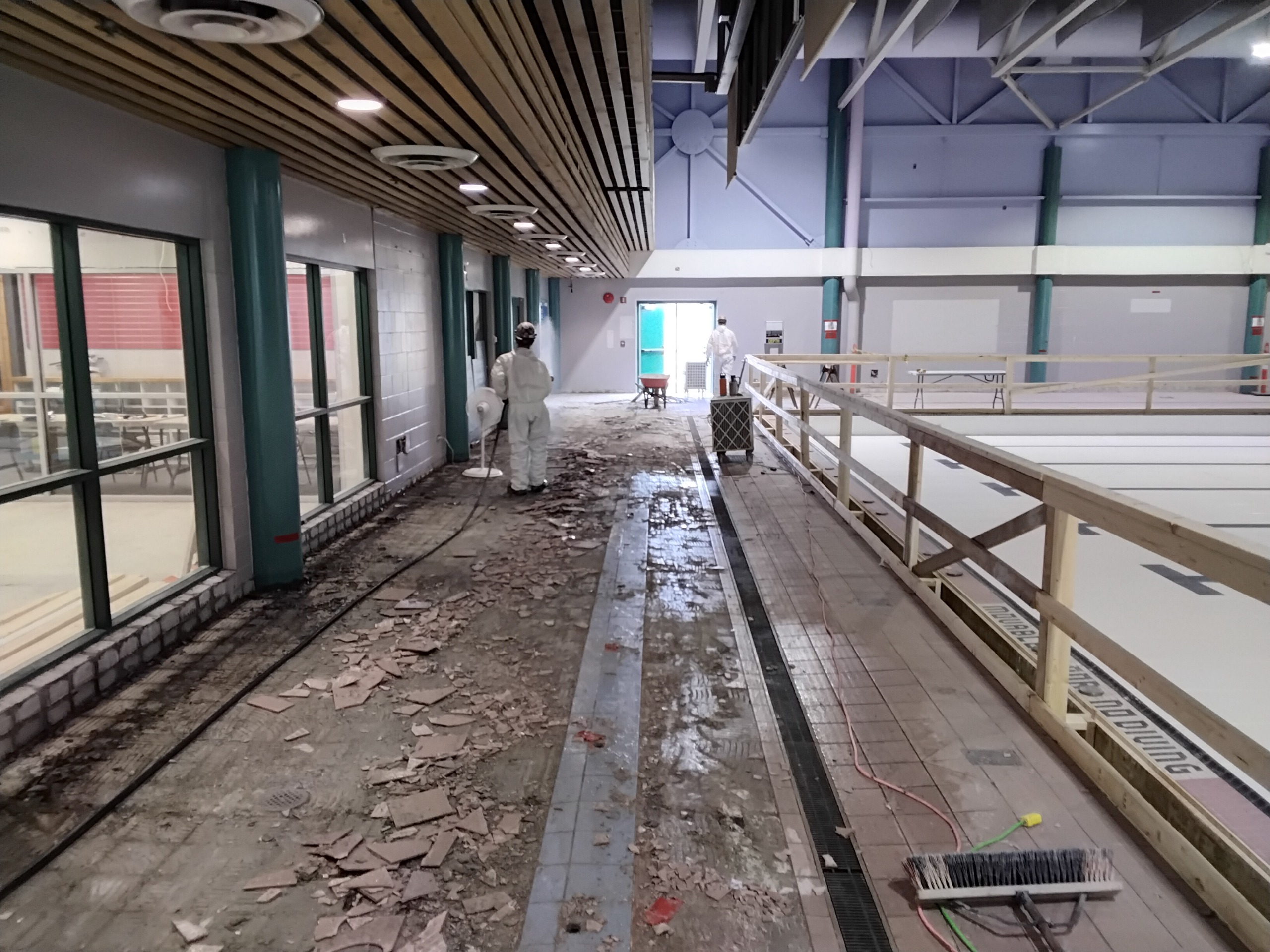 Workers remove tile from the pool deck near the teach pool at the Aquatic Centre